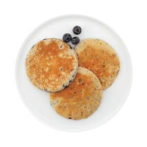 Crêpes aux bleuets Ideal Protein, moelleuses et garnies généreusement de bleuets frais, servies chaudes sur une assiette blanche, parfaites pour un petit déjeuner nourrissant et appétissant.