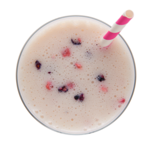 Smoothie aux petits fruits Ideal Protein, présenté dans un verre transparent, débordant de couleurs vibrantes des fruits rouges et bleus, offrant une explosion de goût rafraîchissant et sain pour commencer la journée avec énergie et gourmandise.